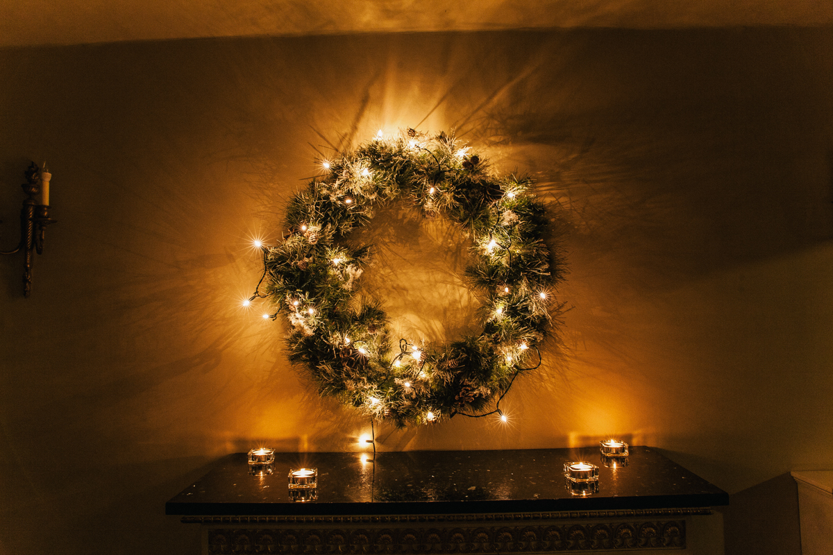 Christmas wedding ceremony space with evergreen garlands and fairy lights