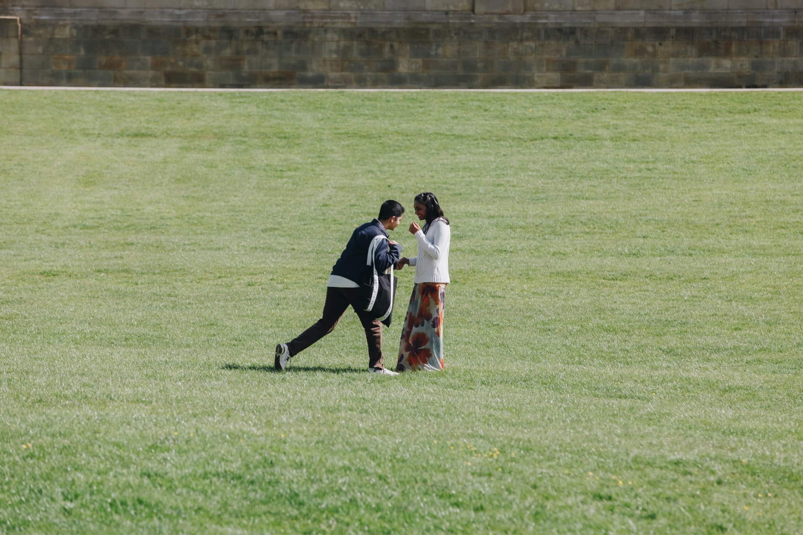 Surprise proposal at Chatsworth House with groom kneeling in front of partner in historic gardens
