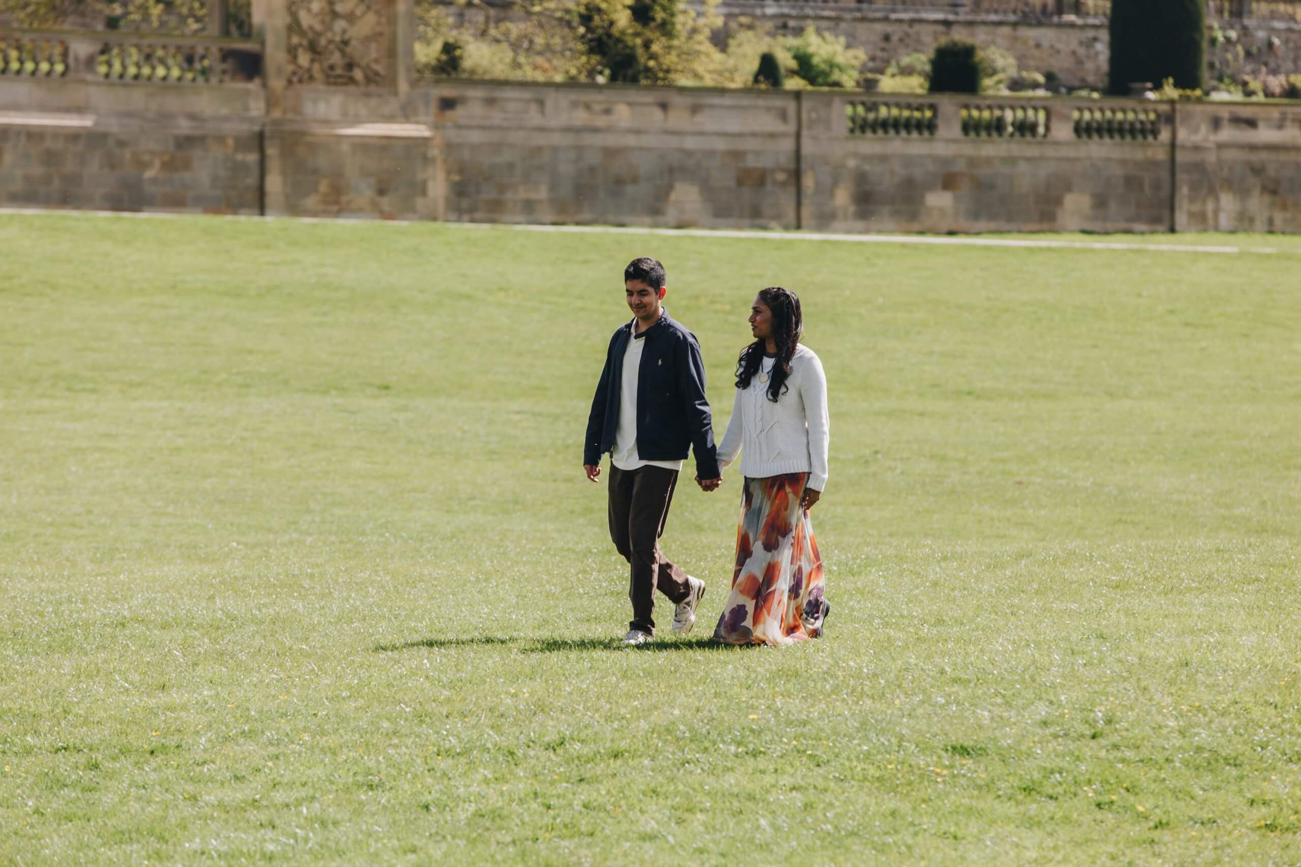 Newly engaged couple walking through Chatsworth House gardens
